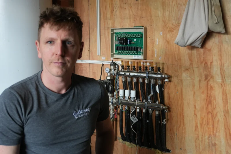 Paul Watson with a labelled Heatmiser underfloor heating manifold on a whole-home automation project
